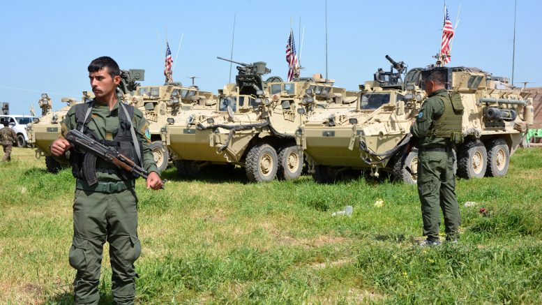 YPG militants stand guard near U.S. armored vehicles in northern Syria in this file photo.