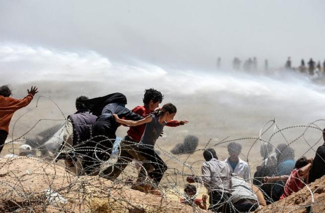 Syrians escape water cannon used by the Turkish border troops