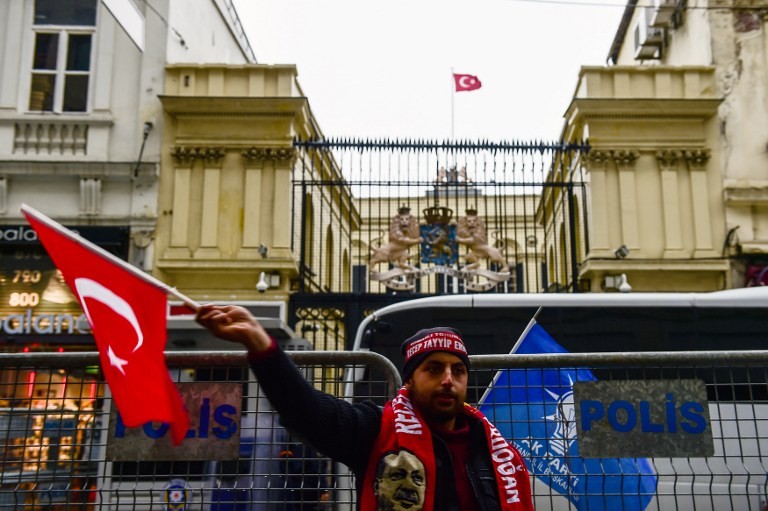 A man waves a Turkish flag in front of the Dutch Consulate