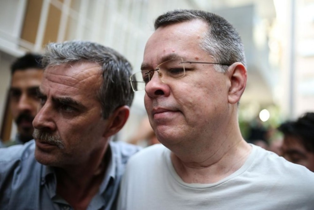 Pastor Andrew Brunson walking through reporters as he is being transported from prison to house arrest.