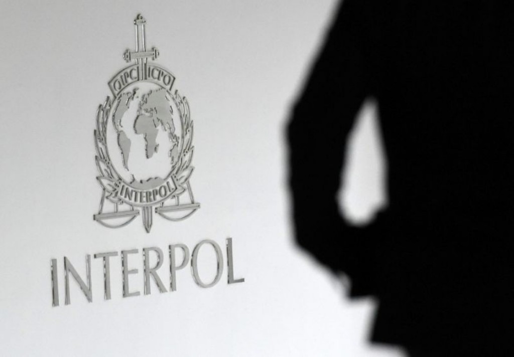 Shadow of a person standing in front of Interpol logo.